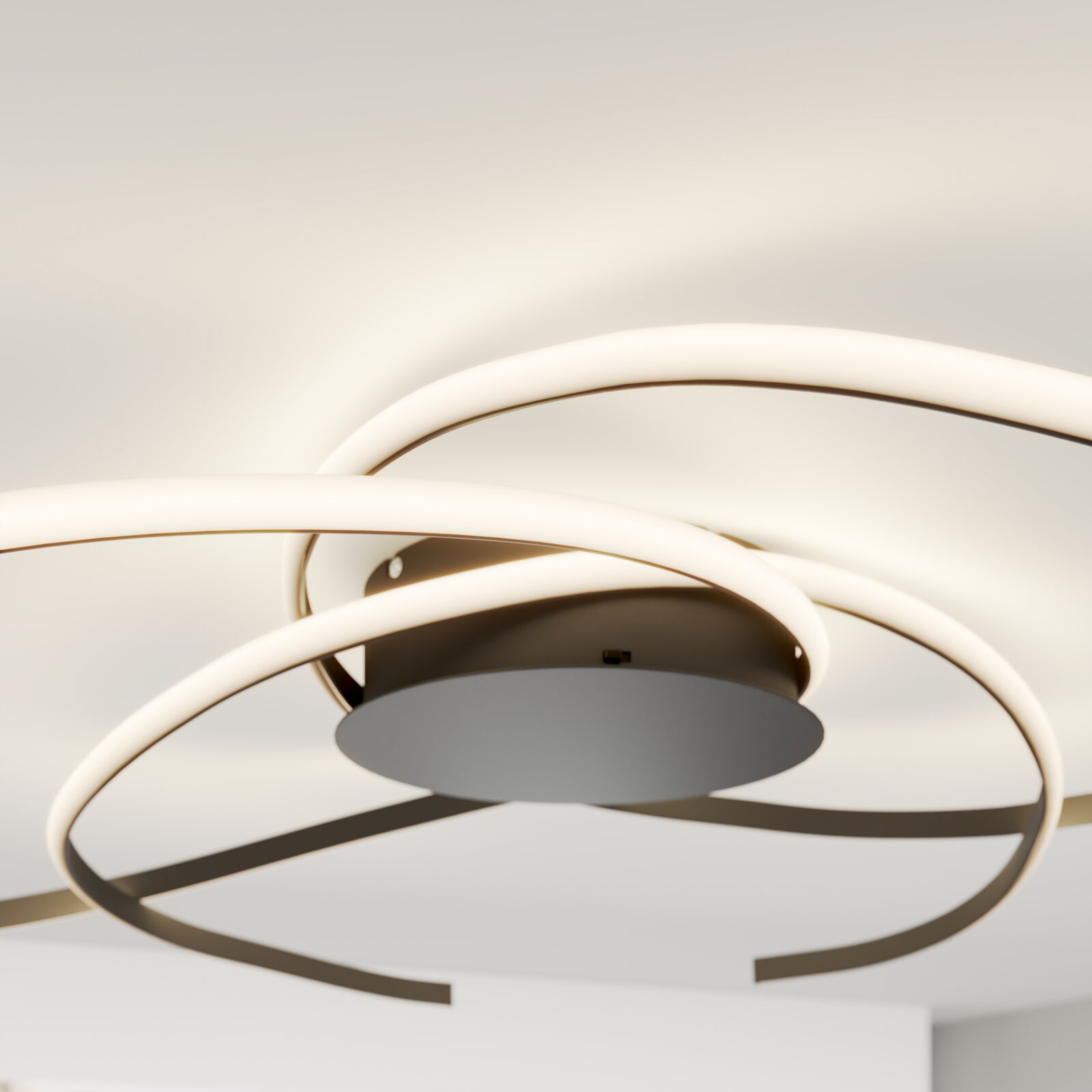 Moderne LED-Deckenleuchte mit drei überlappenden, ringförmigen Lichtbändern in Weiß und Metall, Ansicht von unten in leichter Untersicht