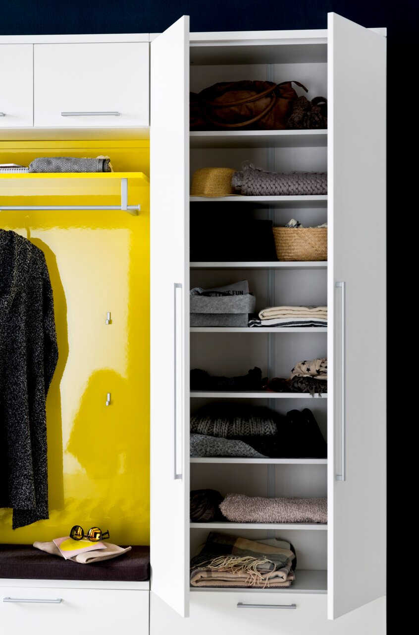 Garderobenschrank mit offenen Türen, gefüllt mit Kleidung und Accessoires, von vorne betrachtet.