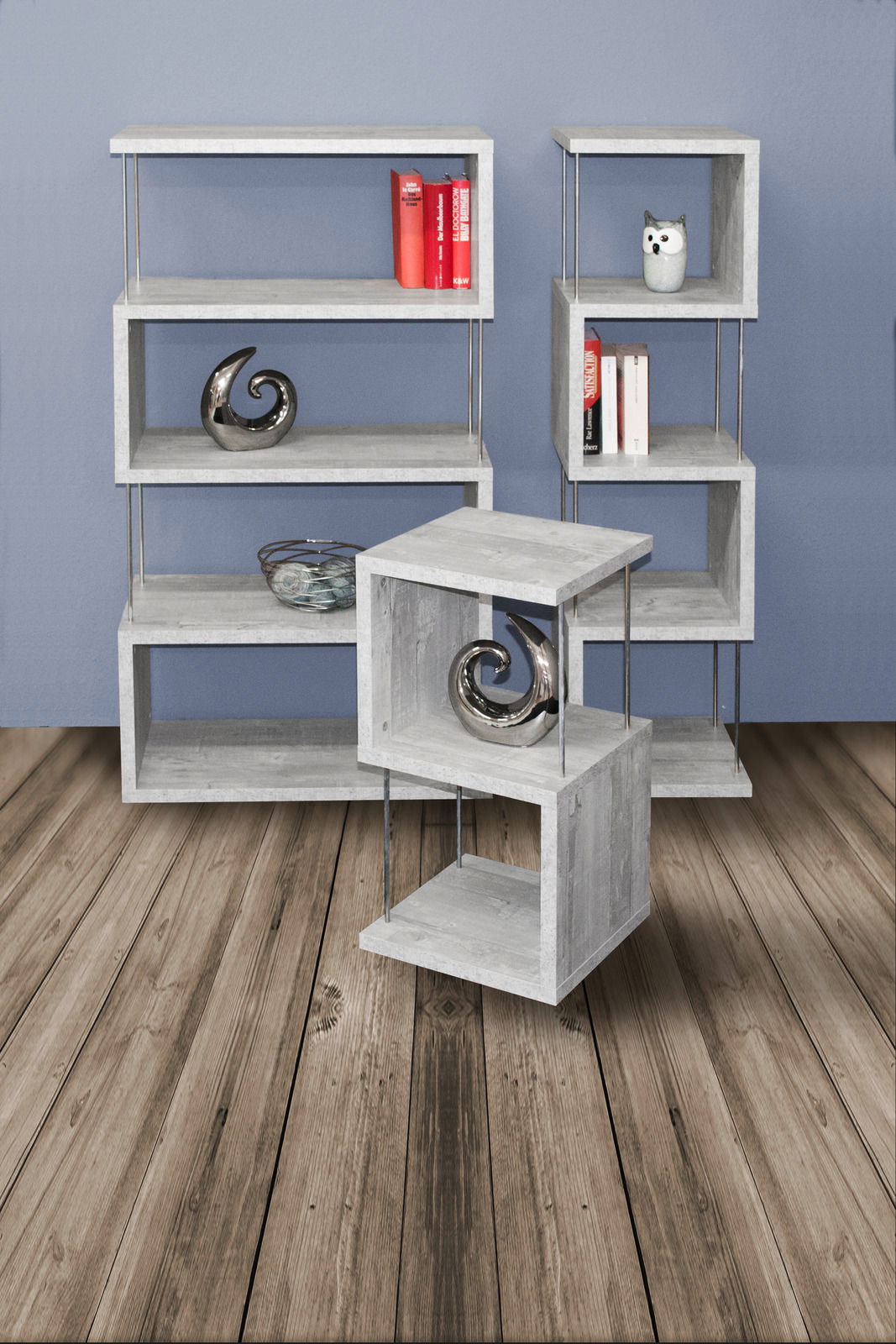 Modernes Standregal-Set aus grauem Holz mit Metallstangen, bestehend aus drei Regalen in verschiedenen Größen, frontal und seitlich betrachtet, auf Holzboden vor blauer Wand.