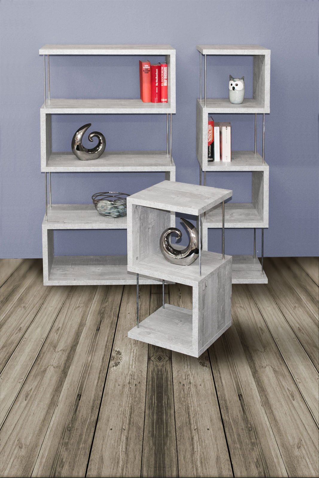 Modernes Standregal-Set aus grauem Holz mit Metallstangen, bestehend aus drei Regalen in verschiedenen Größen, frontal und seitlich betrachtet, auf Holzboden vor blauer Wand.