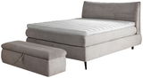 Boxspringbett 180x200 in grauem Stoff mit passendem Hocker, seitliche Perspektive