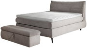 Boxspringbett 180x200 in grauem Stoff mit passendem Hocker, seitliche Perspektive
