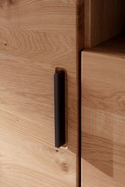 Nahaufnahme eines Holzschranks mit schwarzem Griff, seitliche Perspektive