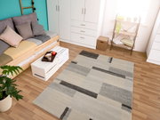 Moderner Frisé-Teppich in einem Wohnzimmer mit geometrischem Muster in Grau- und Beigetönen, aus der Vogelperspektive fotografiert.
