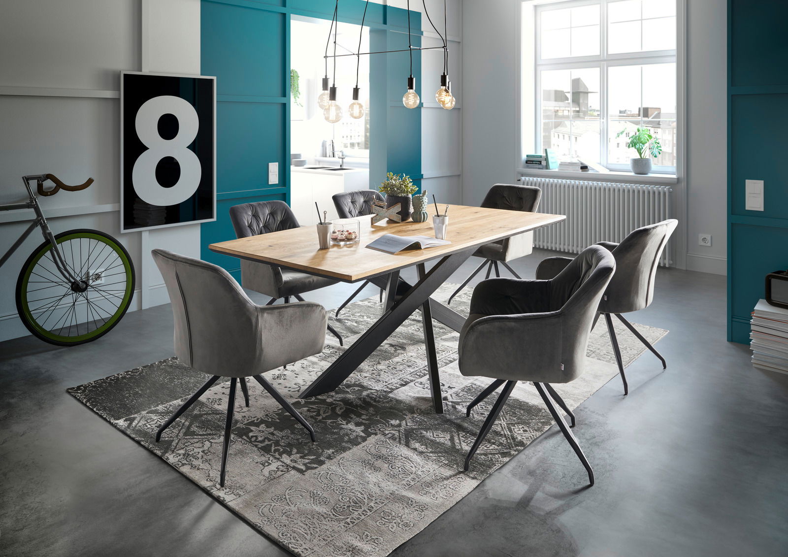 Moderner Esstisch mit Holzplatte und schwarzen Metallbeinen, umgeben von grauen Polsterstühlen in einem stilvoll eingerichteten Raum mit großen Fenstern und dekorativen Elementen. Perspektive: seitliche Ansicht.