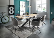 Moderner Esstisch mit Holzplatte und schwarzen Metallbeinen, umgeben von grauen Polsterstühlen in einem stilvoll eingerichteten Raum mit großen Fenstern und dekorativen Elementen. Perspektive: seitliche Ansicht.