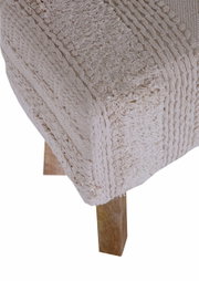 Close-up van een kruk met een gebreide, beige bekleding en houten poten, gezien van bovenaf.
