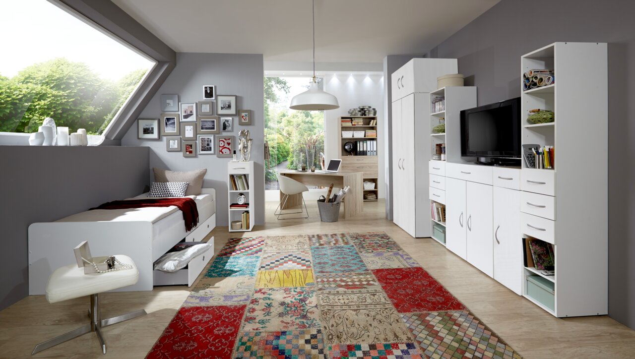 Modernes Schlafzimmer mit Schreibtisch, Bett und Stauraummöbeln in heller, freundlicher Atmosphäre. Perspektive von der Seite mit Blick auf das gesamte Zimmer.