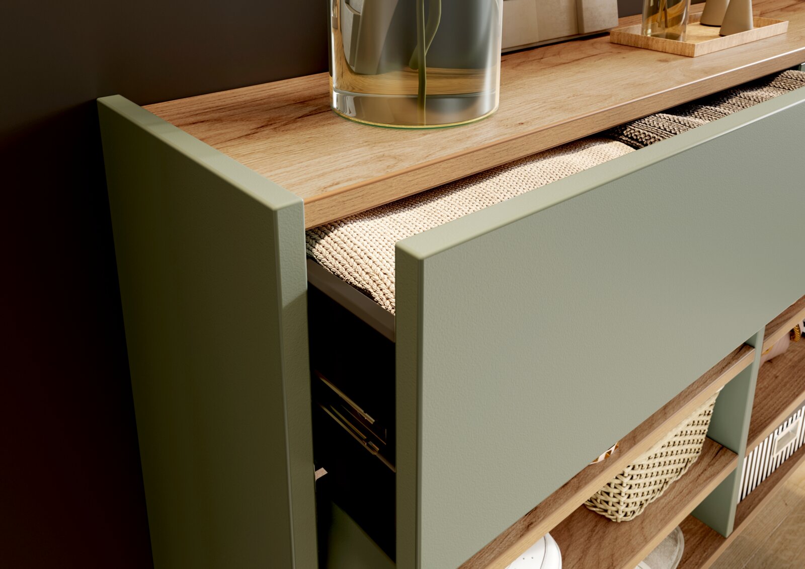 Detailansicht aus schräger Vogelperspektive auf ein geöffnetes Sideboard in Salbeigrün mit Holzplatte, strukturierter Schubladeneinlage und offenen Ablagefächern