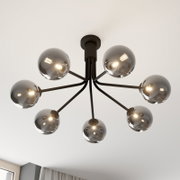 Moderne zwarte plafondlamp met zeven armen en rookgrijze glazen bolkappen, ingeschakeld, gezien van onderaf in een lichte ruimte