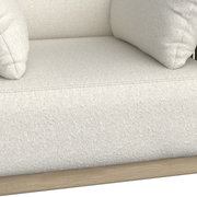 Nahaufnahme eines cremefarbenen Loungesessels mit weicher Polsterung und Holzrahmen, seitliche Perspektive