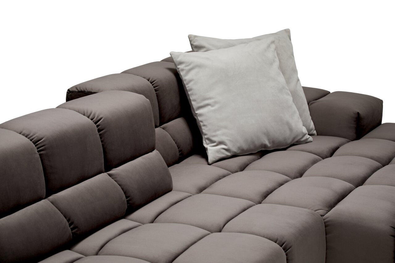 Nahaufnahme einer modernen, grauen Longchairkombination mit gepolsterten Kissen und einer eleganten, gesteppten Oberfläche. Perspektive von schräg oben.