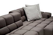Close-up van een moderne, grijze longchair-set met gestoffeerde kussens en een elegant, doorgestikt oppervlak. Weergave vanuit een schuine hoek van bovenaf.