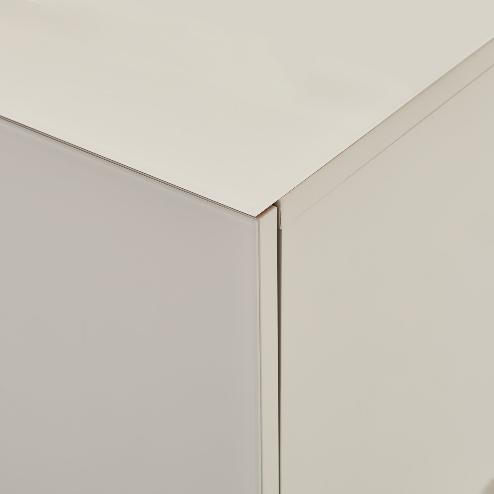 Detailaufnahme einer weißen, minimalistischen Schrank-/Kommodenecke mit glatter Oberfläche, gezeigt aus leicht erhöhter schräger Perspektive