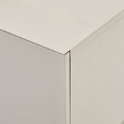 Detailaufnahme einer weißen, minimalistischen Schrank-/Kommodenecke mit glatter Oberfläche, gezeigt aus leicht erhöhter schräger Perspektive