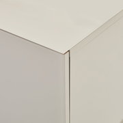 Detailaufnahme einer weißen, minimalistischen Schrank-/Kommodenecke mit glatter Oberfläche, gezeigt aus leicht erhöhter schräger Perspektive