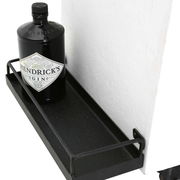 Nahaufnahme eines Barwagens mit einer Flasche Gin auf einem schwarzen Metallregal, seitliche Perspektive.