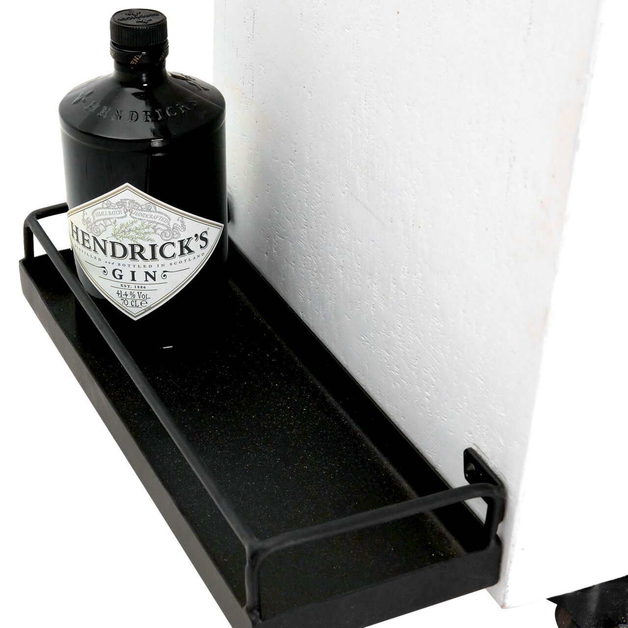 Nahaufnahme eines Barwagens mit einer Flasche Gin auf einem schwarzen Metallregal, seitliche Perspektive.