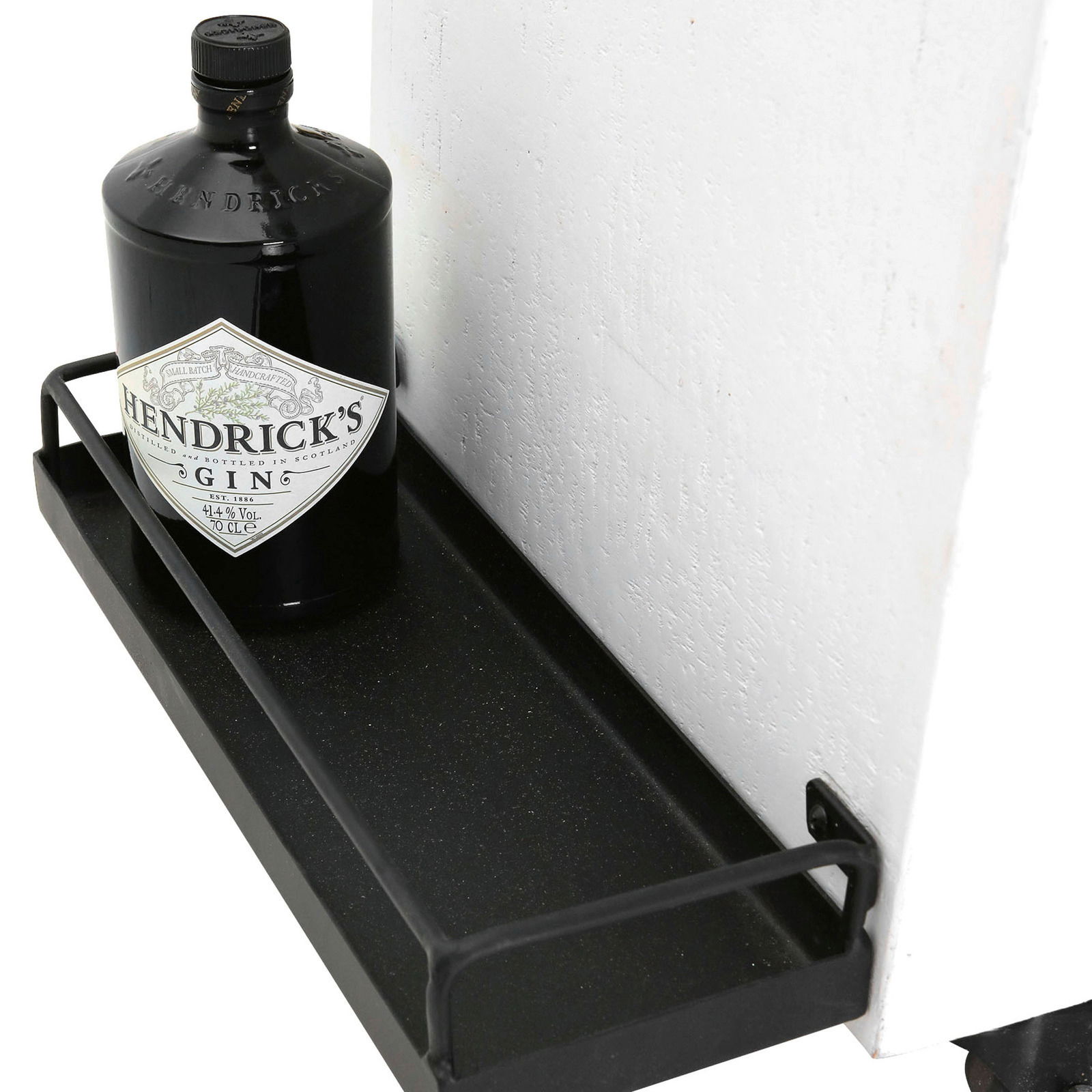 Nahaufnahme eines Barwagens mit einer Flasche Gin auf einem schwarzen Metallregal, seitliche Perspektive.