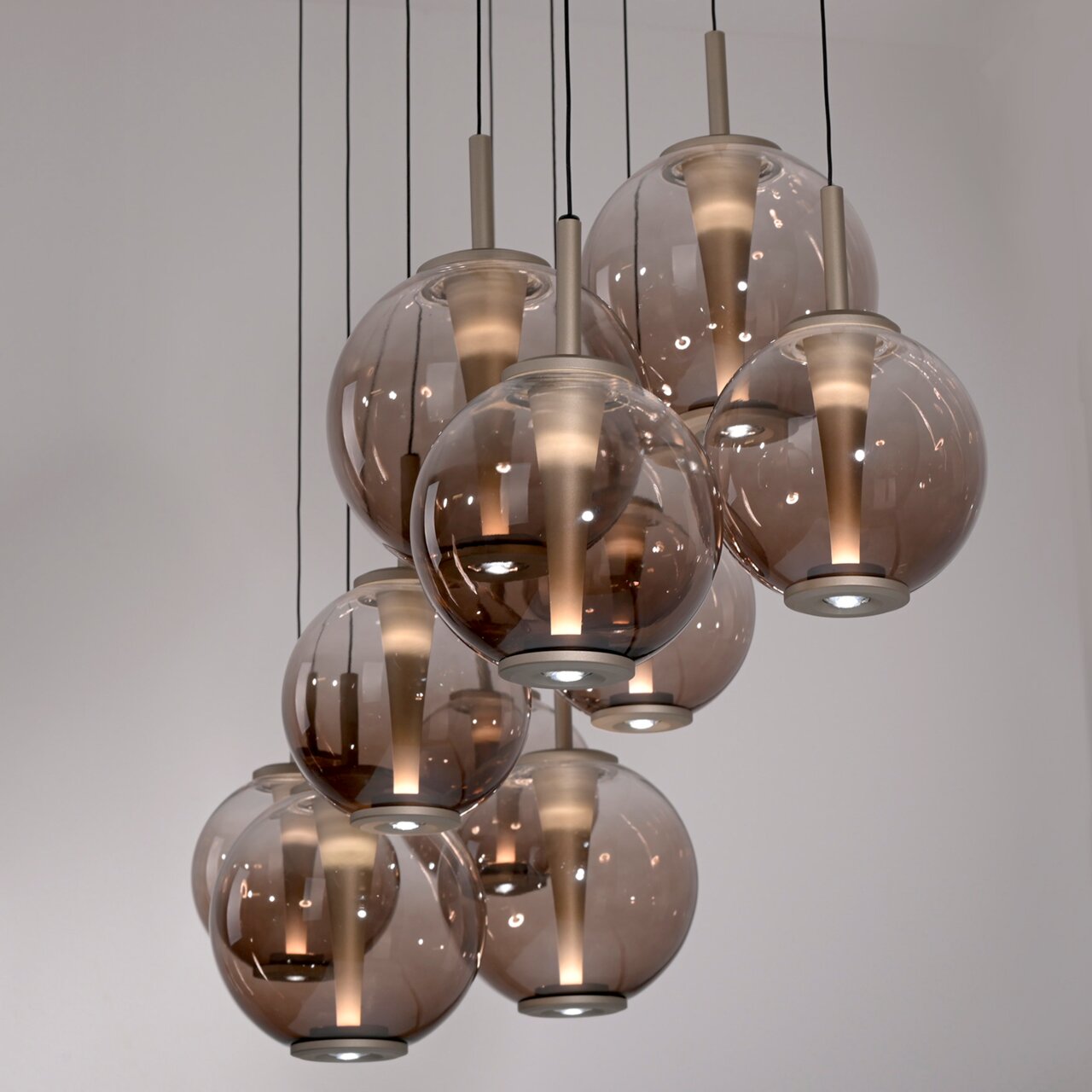 Moderne LED-Pendelleuchte mit mehreren rauchfarbenen Glaskugeln, von unten betrachtet.