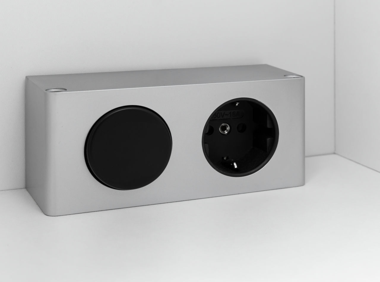 Silberne Steckdose mit schwarzer Abdeckung, seitliche Perspektive
