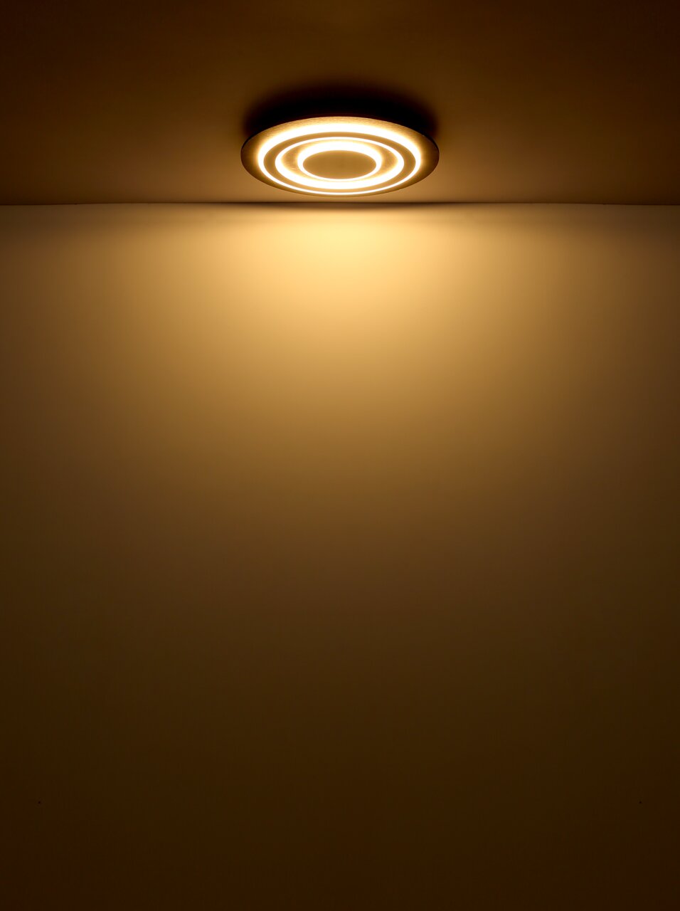 Moderne Deckenleuchte mit kreisförmigem Design, von unten betrachtet, leuchtet warmes Licht ausstrahlend.