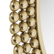 Nahaufnahme eines runden Spiegels mit einem Rahmen aus goldenen Kugeln, seitliche Perspektive.