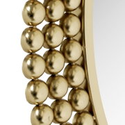 Nahaufnahme eines runden Spiegels mit einem Rahmen aus goldenen Kugeln, seitliche Perspektive.
