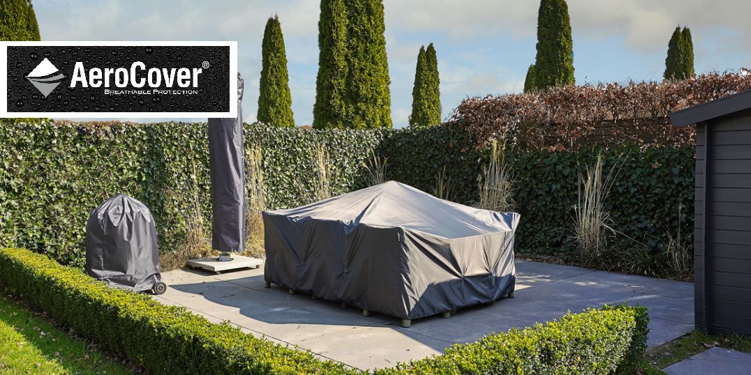 Terrassenbereich im Freien mit AeroCover-Schutzhüllen für Möbel, umgeben von Grün und einem Gartenhaus.