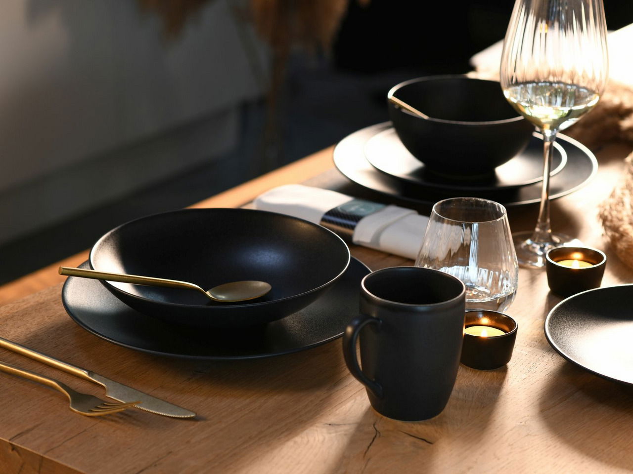 Elegantes Kombiservice Soft Touch 20-tlg in Schwarz auf einem gedeckten Tisch, seitliche Perspektive.