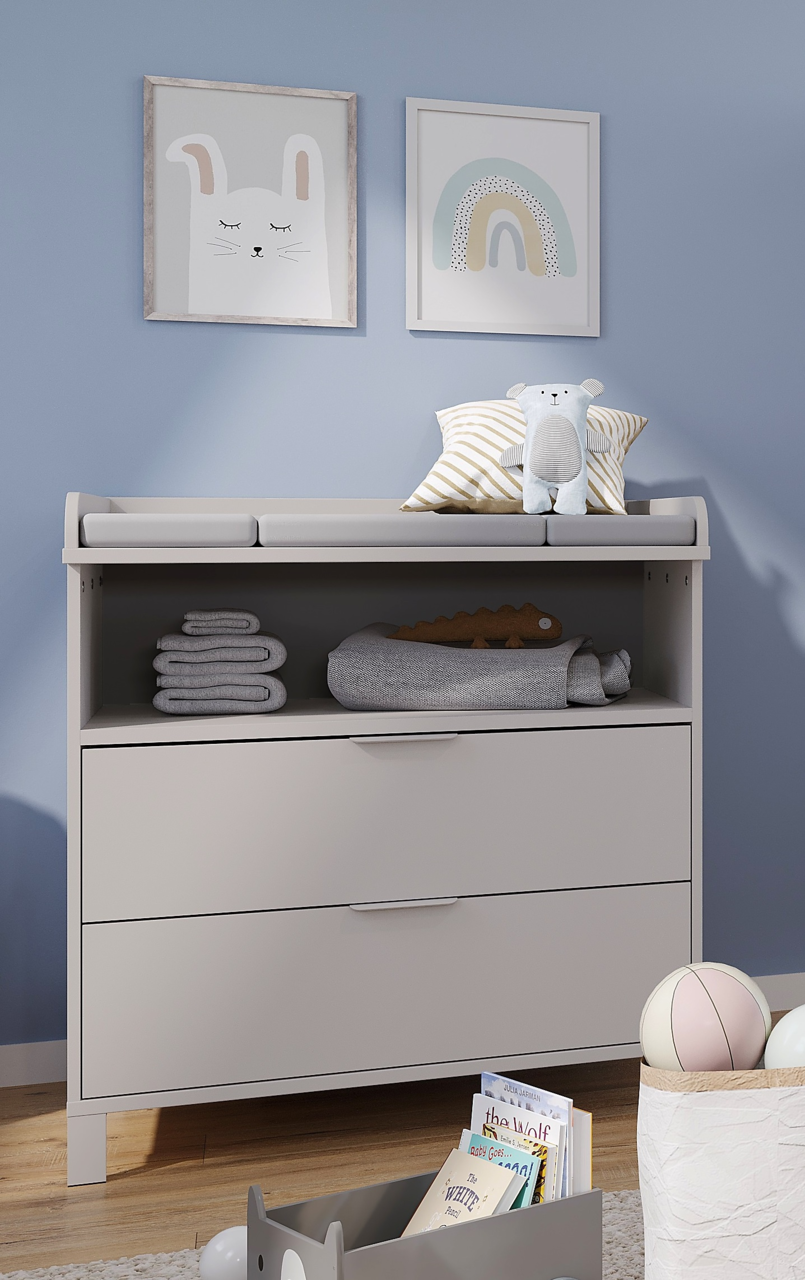 Wickelaufsatz schmal auf einer Kommode, mit Stofftieren und Handtüchern dekoriert, aus der Frontalperspektive.