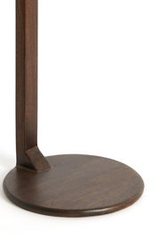 Nahaufnahme eines runden, dunklen Holzfußes eines Beistelltisches, von der Seite betrachtet.