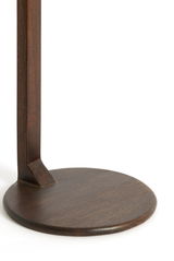 Nahaufnahme eines runden, dunklen Holzfußes eines Beistelltisches, von der Seite betrachtet.