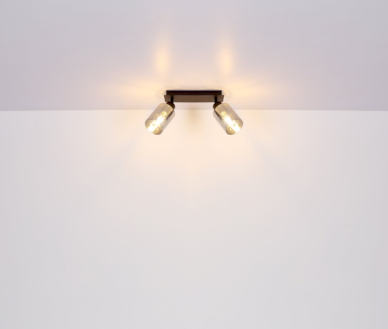 Zweiflammiger Strahler aus schwarzem Metall, matt, an der Decke montiert, mit warmem Licht, seitliche Perspektive.