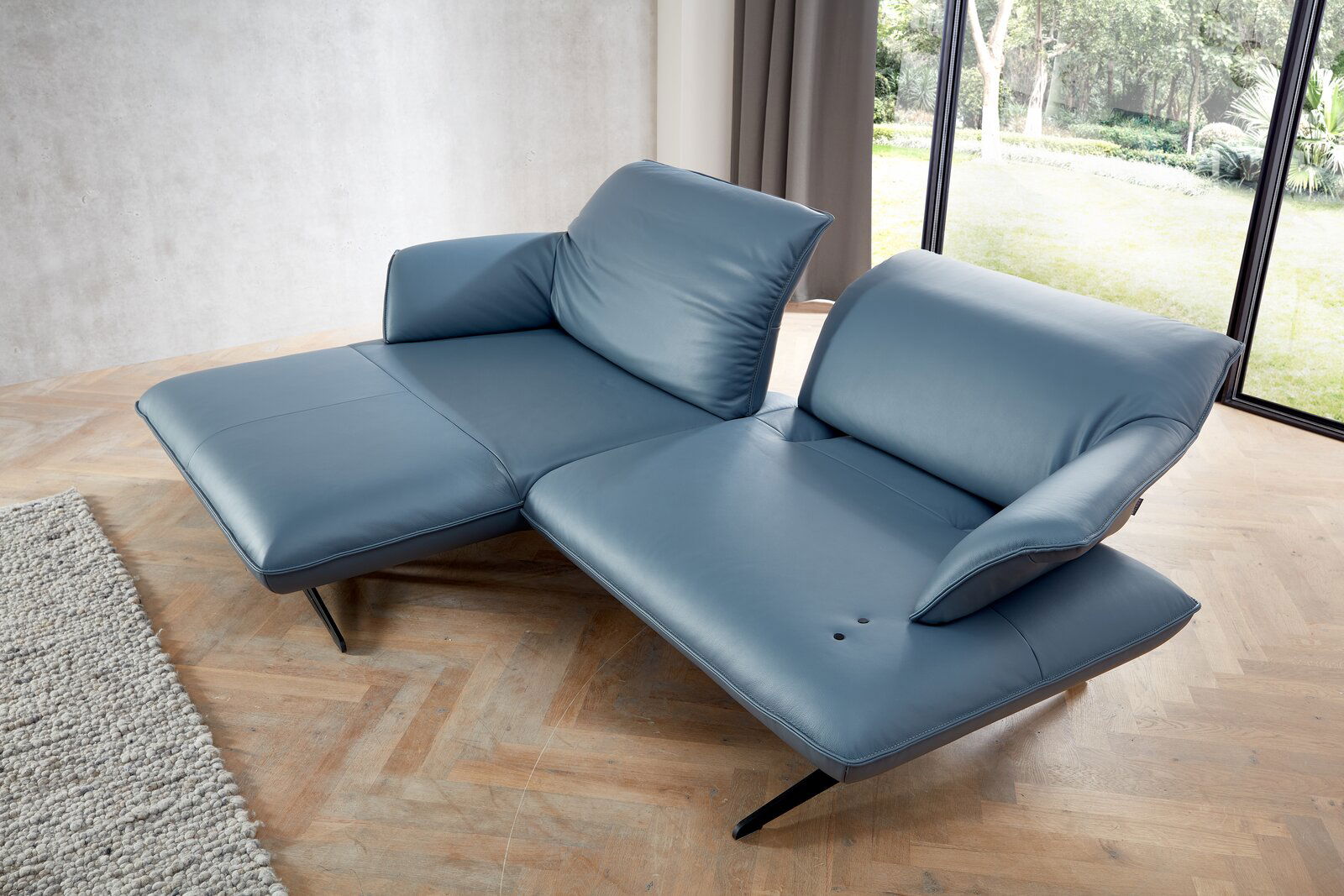 Blaue Longchairkombination Koinor SEVENTY in moderner Wohnzimmerumgebung, seitliche Perspektive mit Blick auf die Fensterfront.