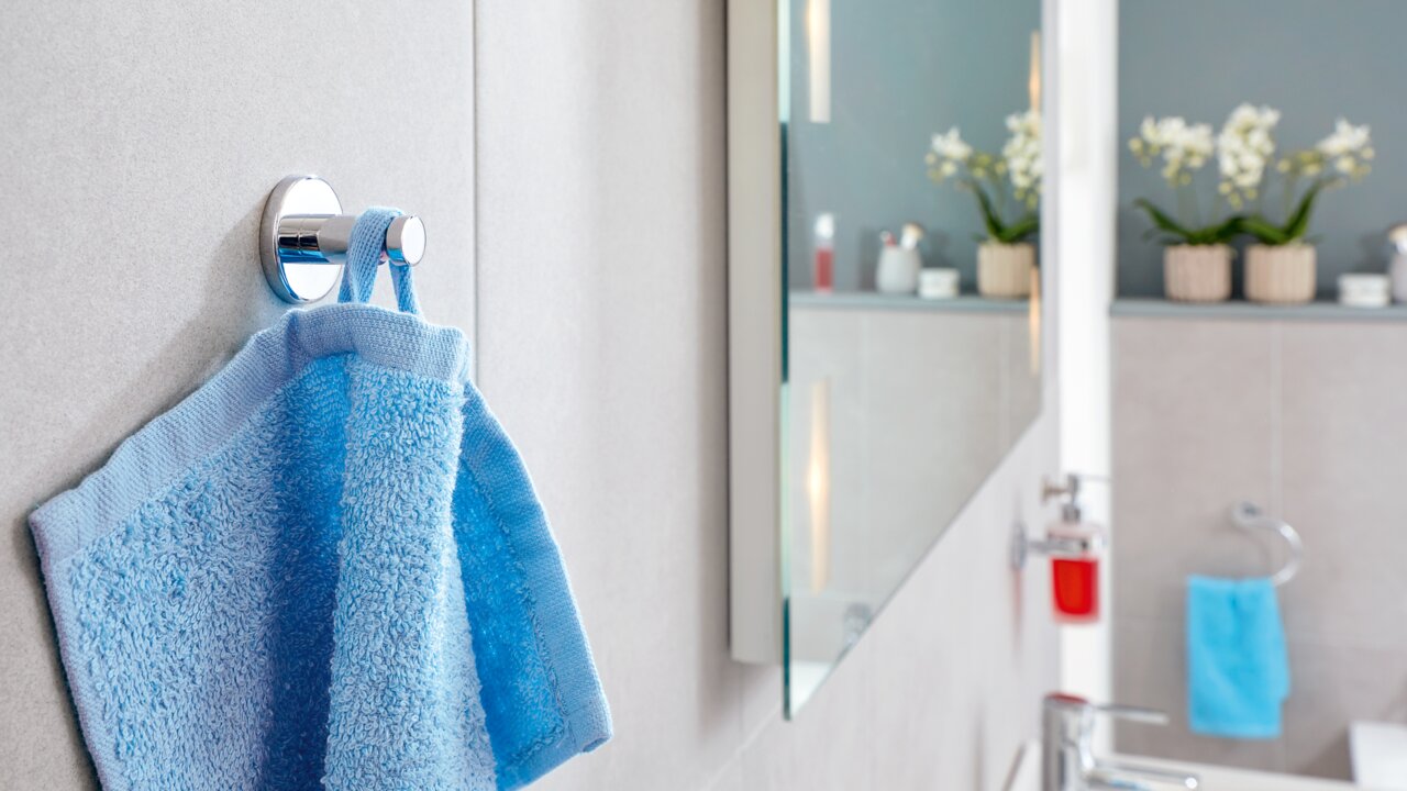 Moderner Handtuchhaken aus Chrom mit blauem Handtuch, seitliche Perspektive im Badezimmer.