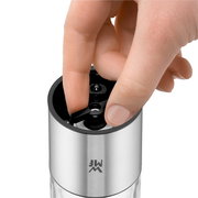 Nahaufnahme einer Hand, die eine elektrische Mühle bedient, mit Fokus auf den Einstellmechanismus.