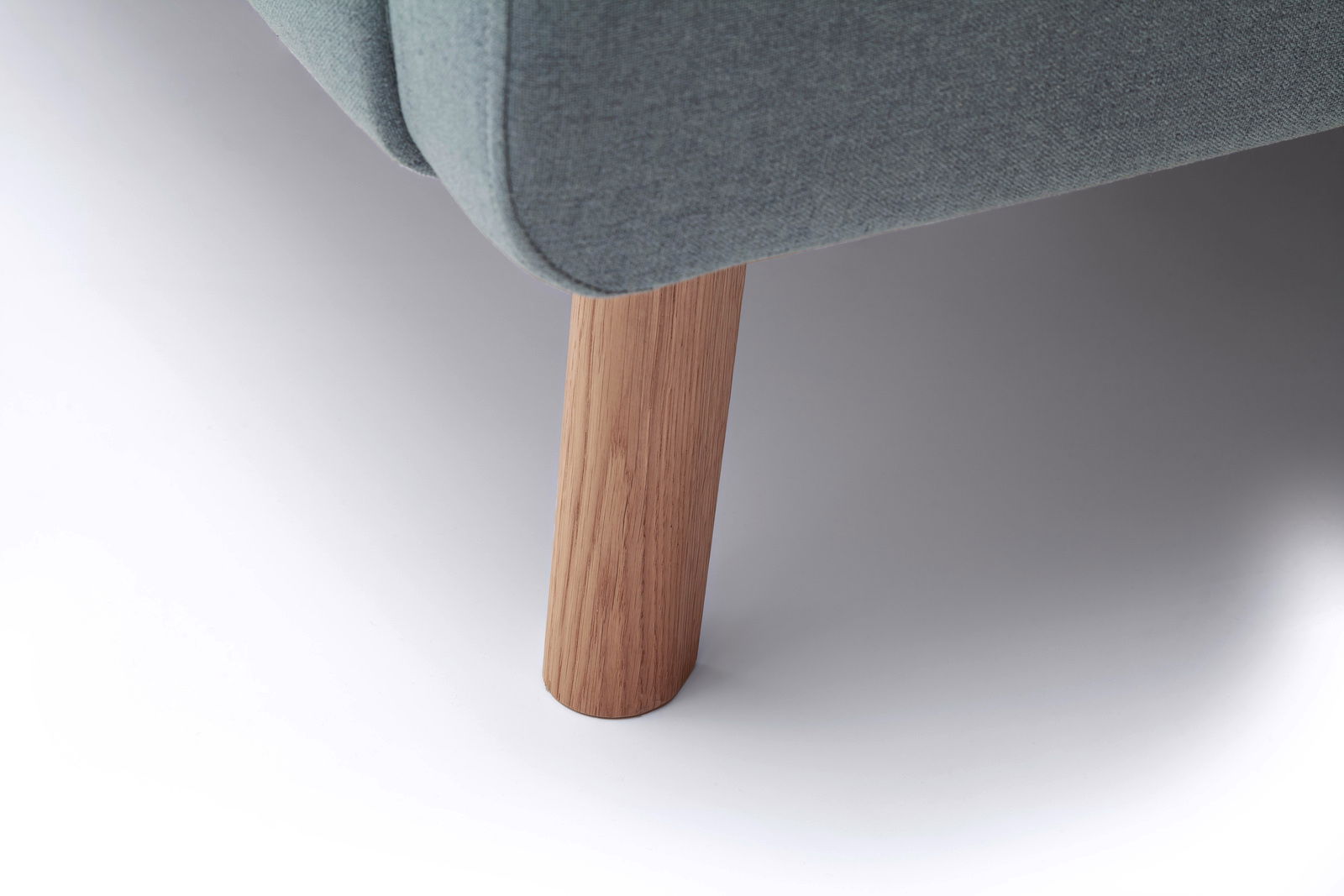 Nahaufnahme eines Polsterbettbeins aus Holz mit grauem Stoffbezug, seitliche Perspektive