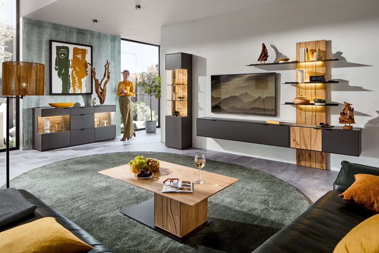 Moderne Wohnzimmer-Wandkombination mit Holz- und Glaselementen, stilvoll dekoriert, aus der Perspektive eines gemütlichen Wohnzimmers mit Teppich und Couchtisch.