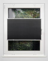 Schwarzes Plissee am Fenster, halb heruntergelassen, mit Blick auf einen Garten im Hintergrund.