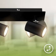 Mat zwarte plafondlamp met drie draaibare cilindervormige spots, van schuin onderen bekeken terwijl de lampen branden