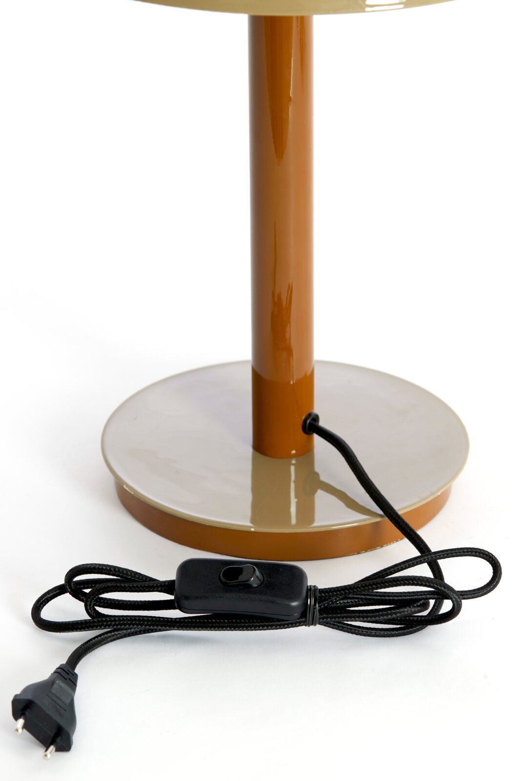 Close-up van de voet van een tafellamp met een bruine voet en een zwarte kabel met schakelaar.