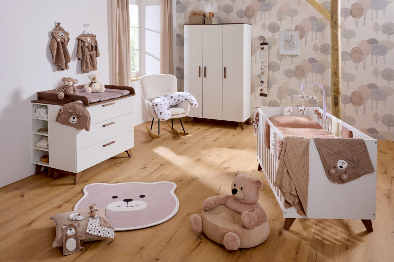 JIMMYLEE Babybett EMELY Gemütliches Babyzimmer mit einem weißen Babybett, umgeben von weichen Stofftieren und neutralen Farben, aus der Perspektive eines einladenden, warmen Raumes.