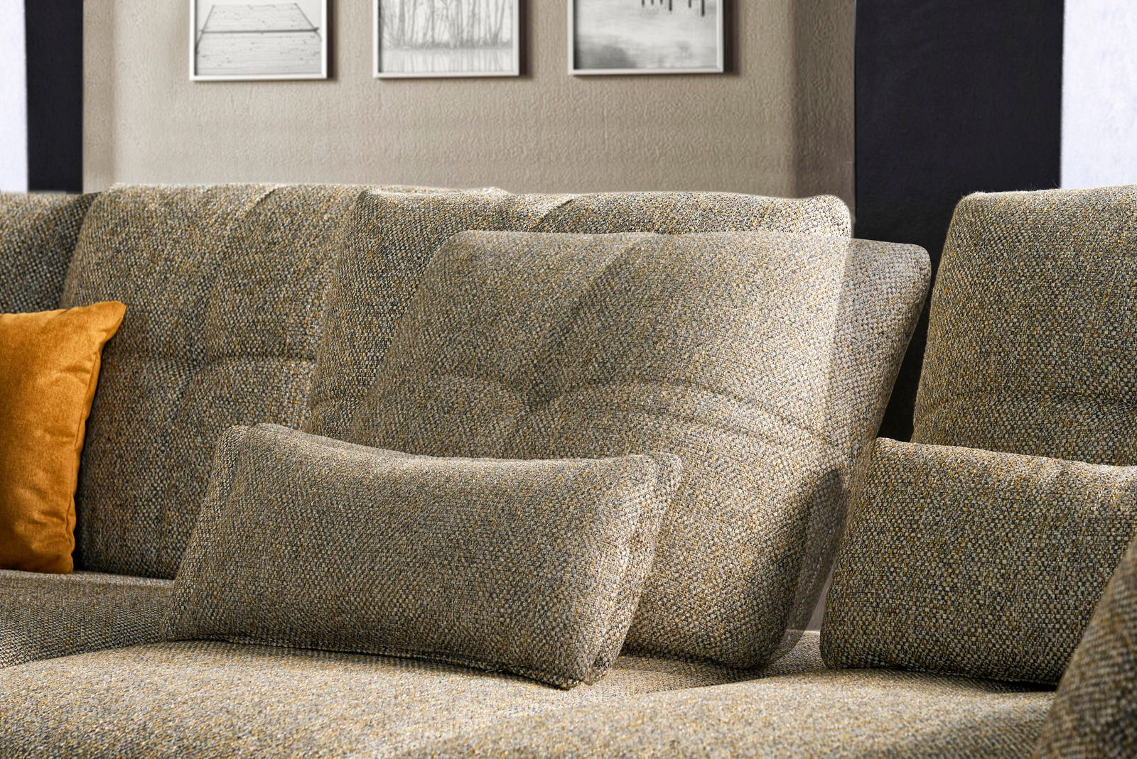 Nahaufnahme einer gemütlichen Rundecke mit strukturiertem Stoffbezug in neutralen Tönen, ergänzt durch ein orangefarbenes Kissen.