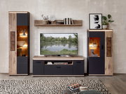 Frontale Ansicht einer modernen Wohnwand im Wohnzimmer: TV-Lowboard mit Fernseher, zwei Vitrinenschränke und Wandregal in Holzoptik und Anthrazit mit integrierter LED-Beleuchtung.