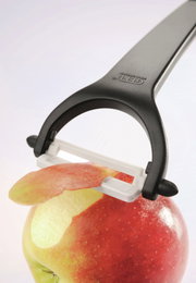 Keramikschäler Ceramo in Nahaufnahme, der die Schale eines Apfels entfernt.