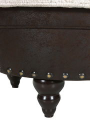 Nahaufnahme eines Hockers mit dunklen Holzbeinen und dekorativen Nieten, seitliche Perspektive.