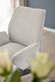 Nahaufnahme eines Armlehnstuhls mit hellgrauem, geripptem Stoffbezug, seitliche Perspektive