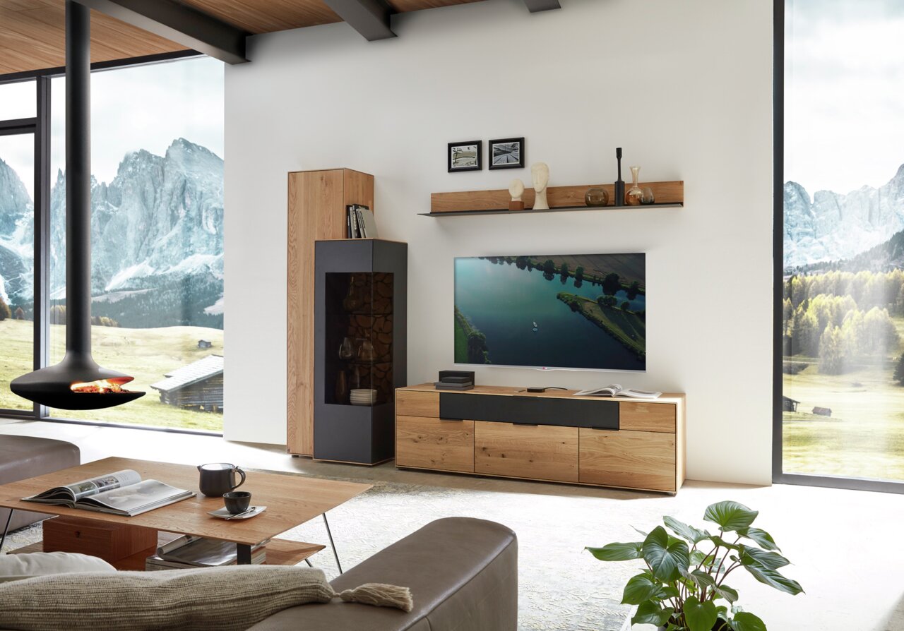 Wöstmann Markenmöbel Wandbord WM 2140 Modernes Wohnzimmer mit Wandbord in Holzoptik, dekoriert mit Büchern und Skulpturen, aus seitlicher Perspektive.