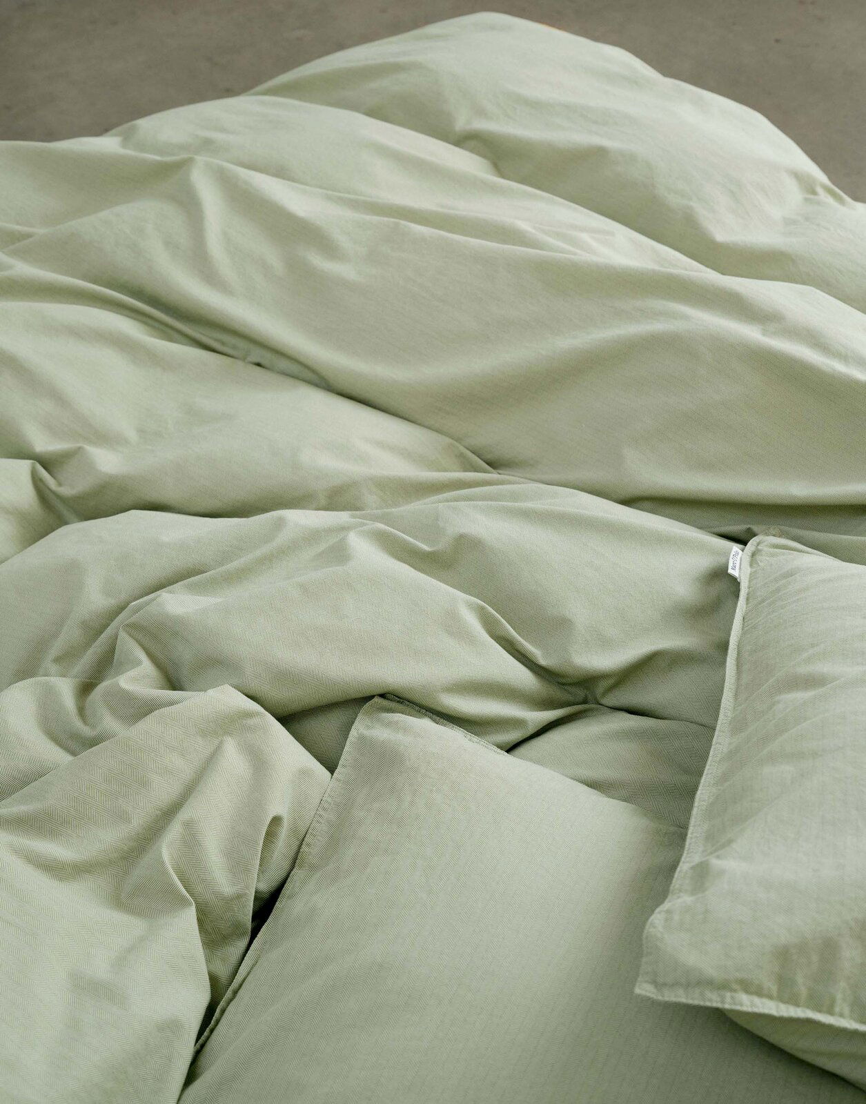 Grüne Bettwäsche 135x200cm aus der Vogelperspektive, weich und einladend drapiert.